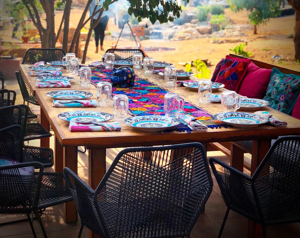 Outside dining table, set with colorful plates, at Metate Cabo