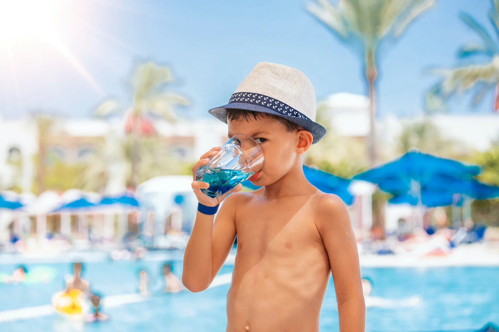 Boy drinking water by a pool in Cabo San Lucas