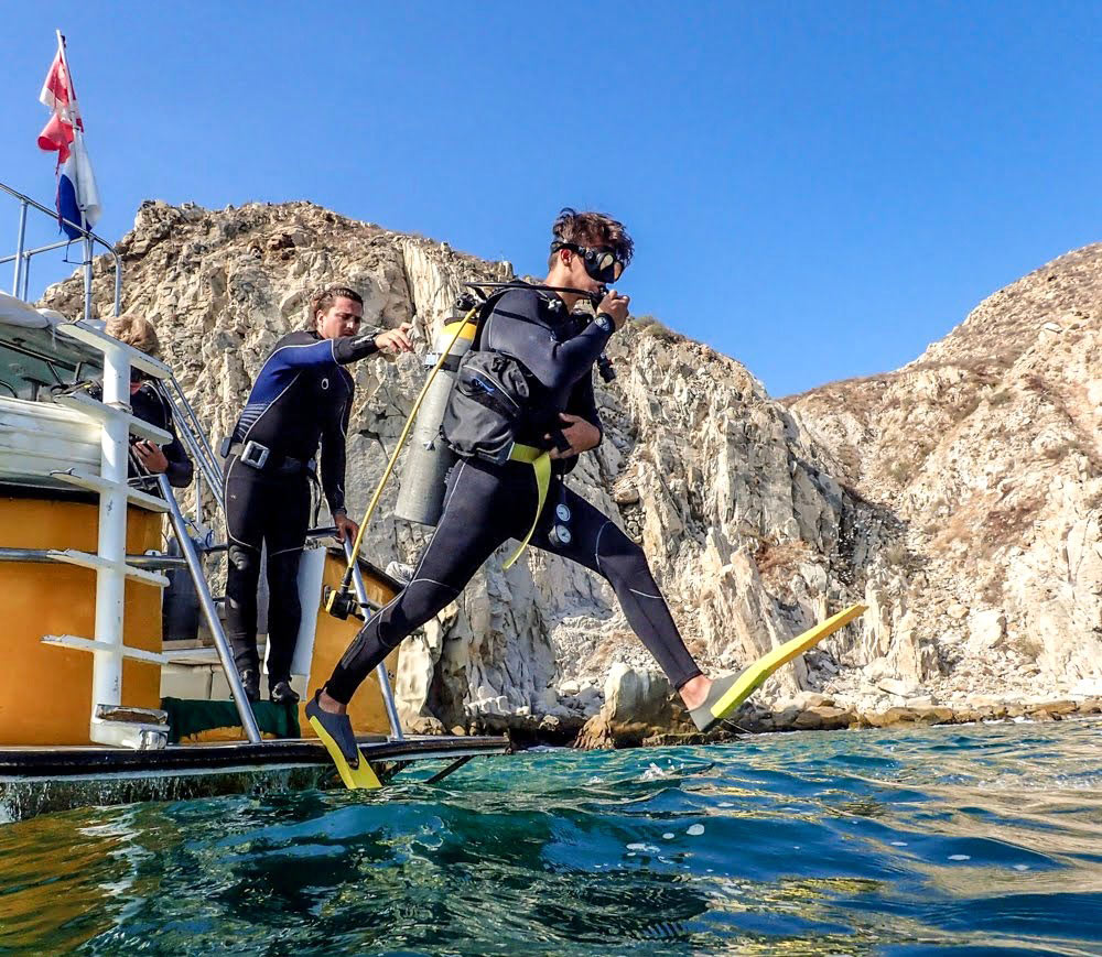 A scuba diver jumps off the boat to descend under the water at Land's End, Cabo San Lucas.