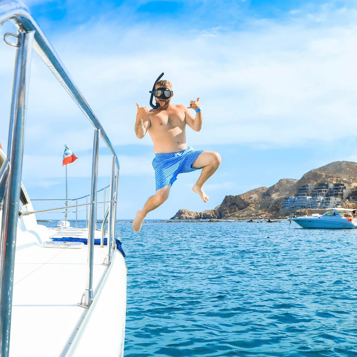 Happy snorkeler jumping off a boat into the water in Cabo San Lucas.