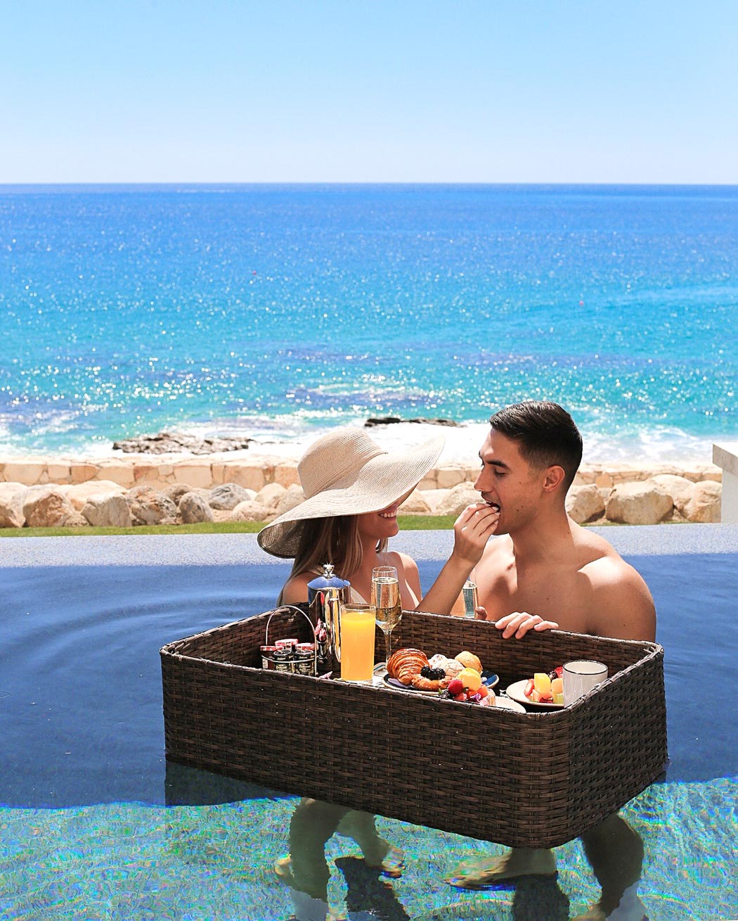 A couple enjoy a floating breakfast in their private pool at Hilton Los Cabos.