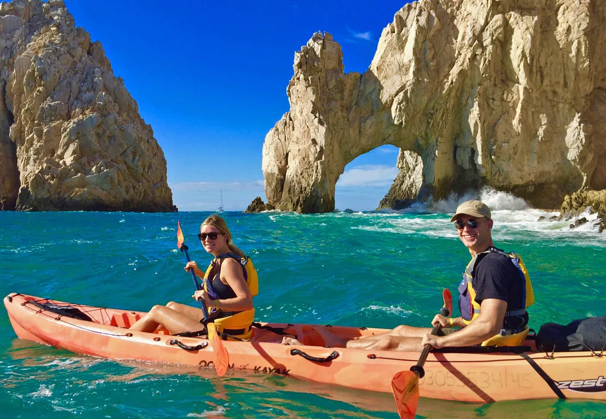 A couple in a double kayak by the Los Cabos Arch