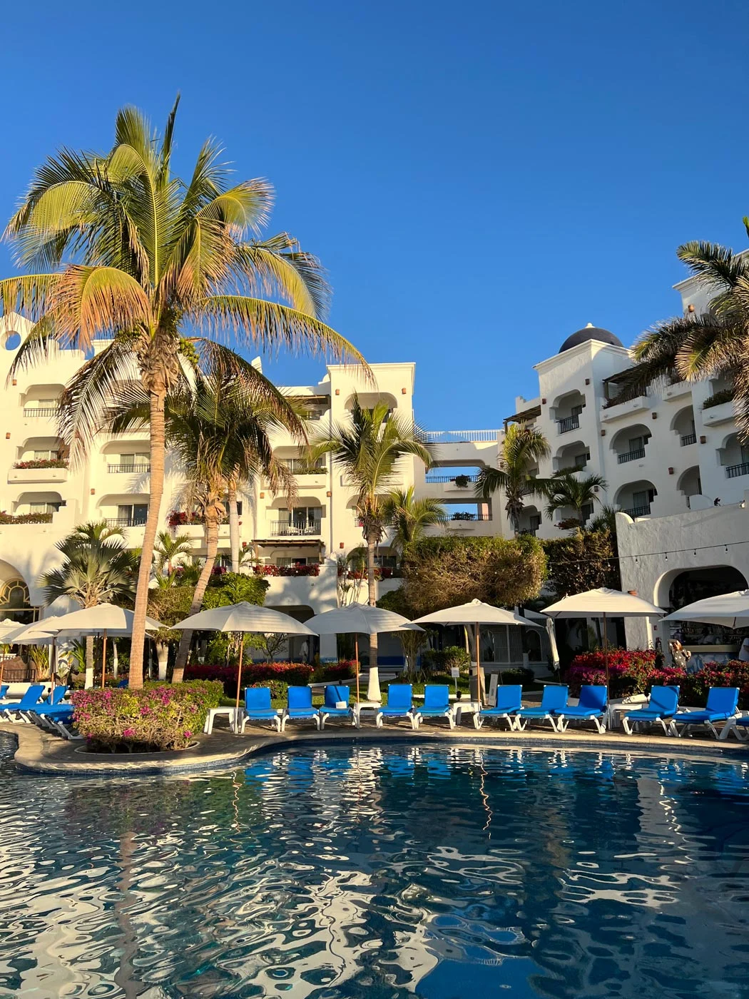 Blue-cushioned lounge chairs around the pool at Pueblo Bonito Los Cabos