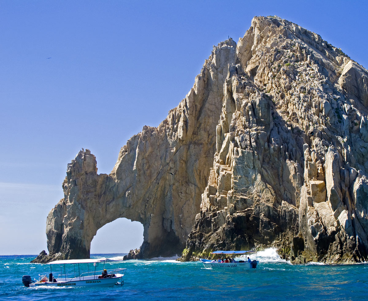 Water taxi boats cruise by the Cabo San Lucas Arch.