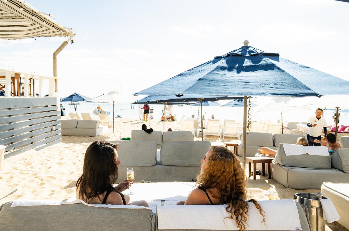 Two young women lounging at Corazon Beach Club in Cabo San Lucas