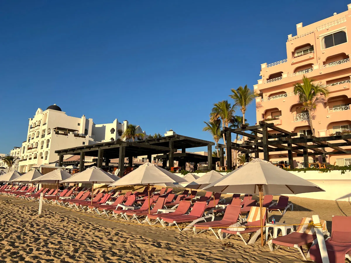 Pink beach chairs in front of the side-by-side Pueblo Bonito Los Cabos and Pueblo Bonito Rose resorts on Medano Beach