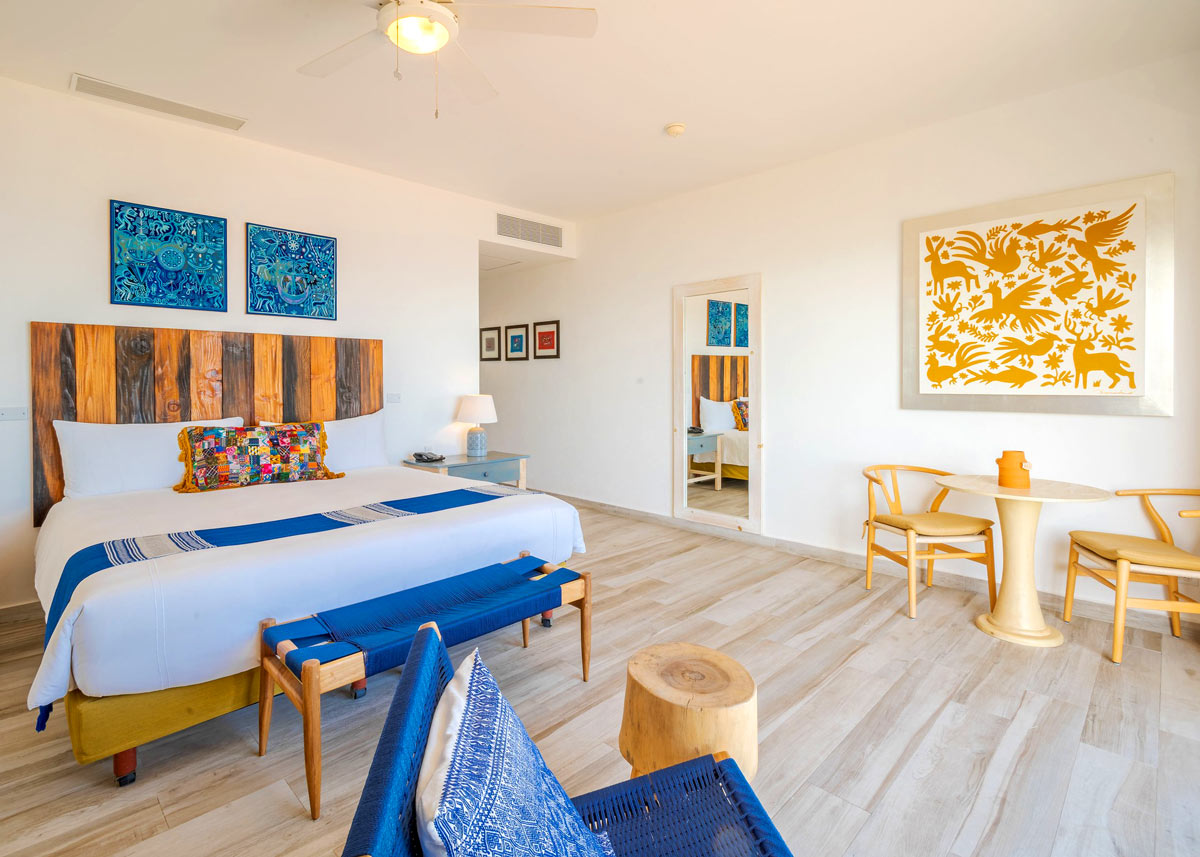 Mar del Cabo guest room with a king bed and yellow and blue art on the white walls