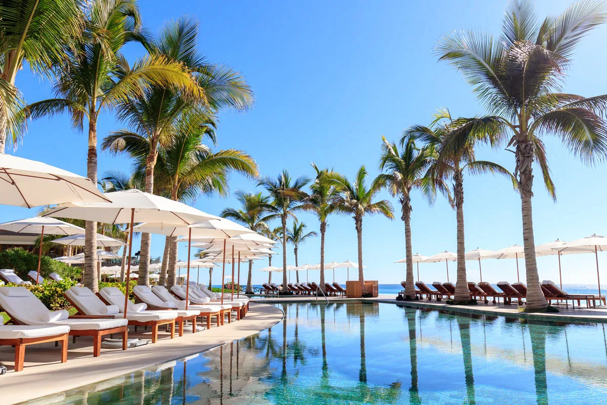 Swimming pool at Grand Velas Los Cabos, surrounded by pool chairs with white umbrellas