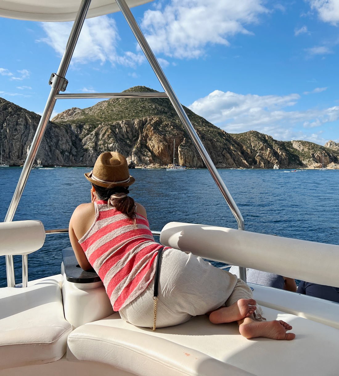 Woman on boat wearing red T-Shirt looks for whales in Cabo San Lucas