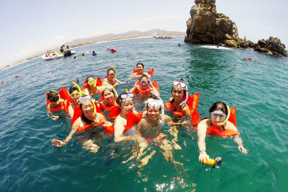 Group of young women in red life jackets snorkeling at Pelican Rock