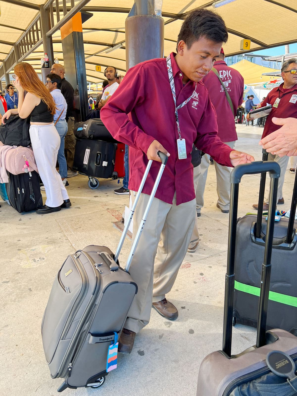 Cabo airport transfer greeter in burgundy shirt with suitcase