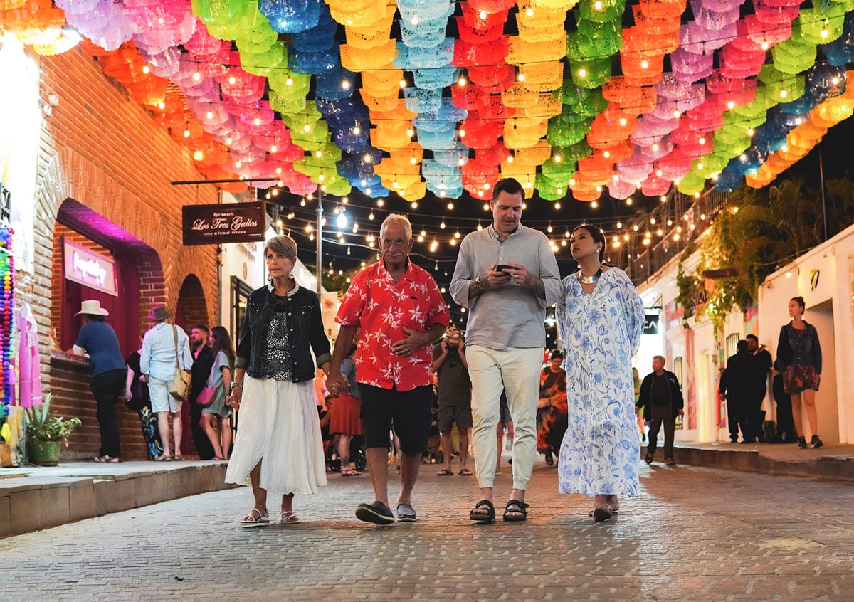 People stroll beneath colorful papel picado during the free San José del Cabo Art Walk.