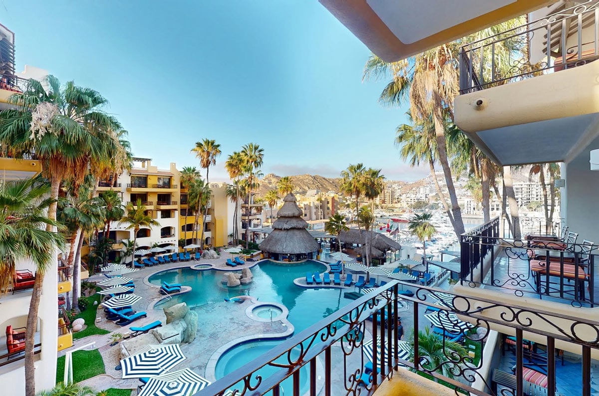 Bright blue pool loungers and palapa pool bar at Marina Fiesta Resort, overlooking the Cabo San Lucas Marina